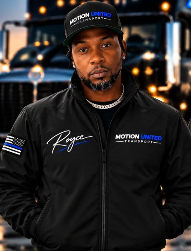 Royce, co-founder of Motion United Transport, in a branded jacket in front of a truck